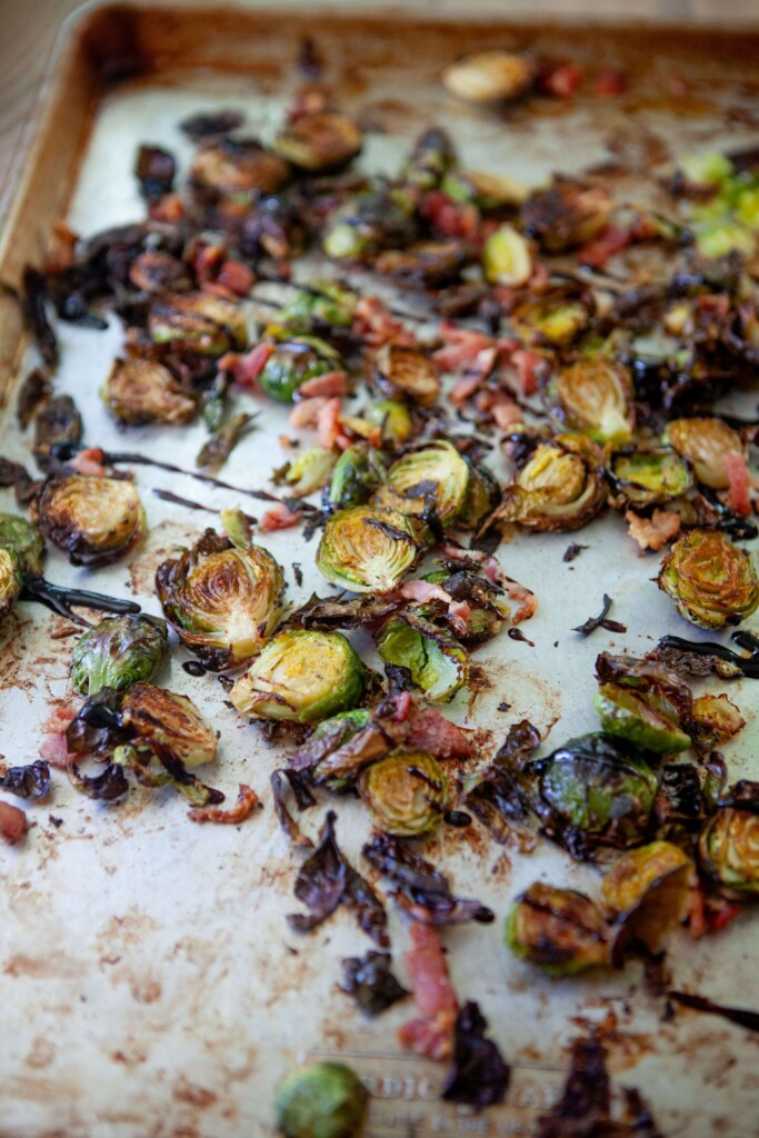 Roasted brussels and bacon on sheet pan drizzled with balsamic glaze.