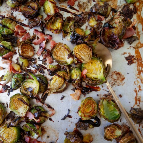 Roasted brussels sprouts on pan drizzled with balsamic glaze.
