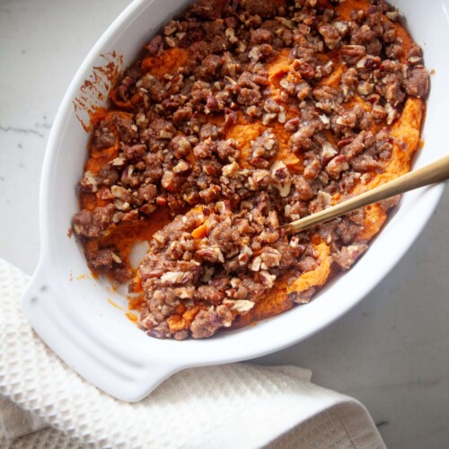 Healthier sweet potato casserole in baking dish with gold spoon.