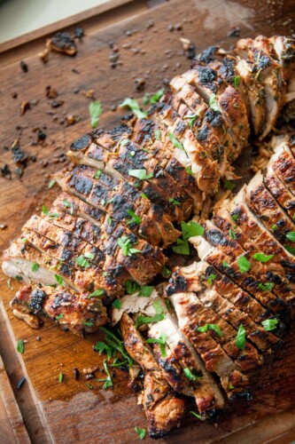 Balsamic and herb pork tenderloin sliced and garnished with fresh herbs.