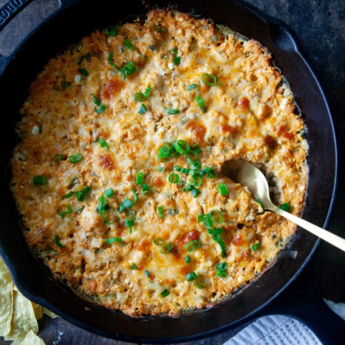 Buffalo chicken dip baked in cast iron skillet with spoon.