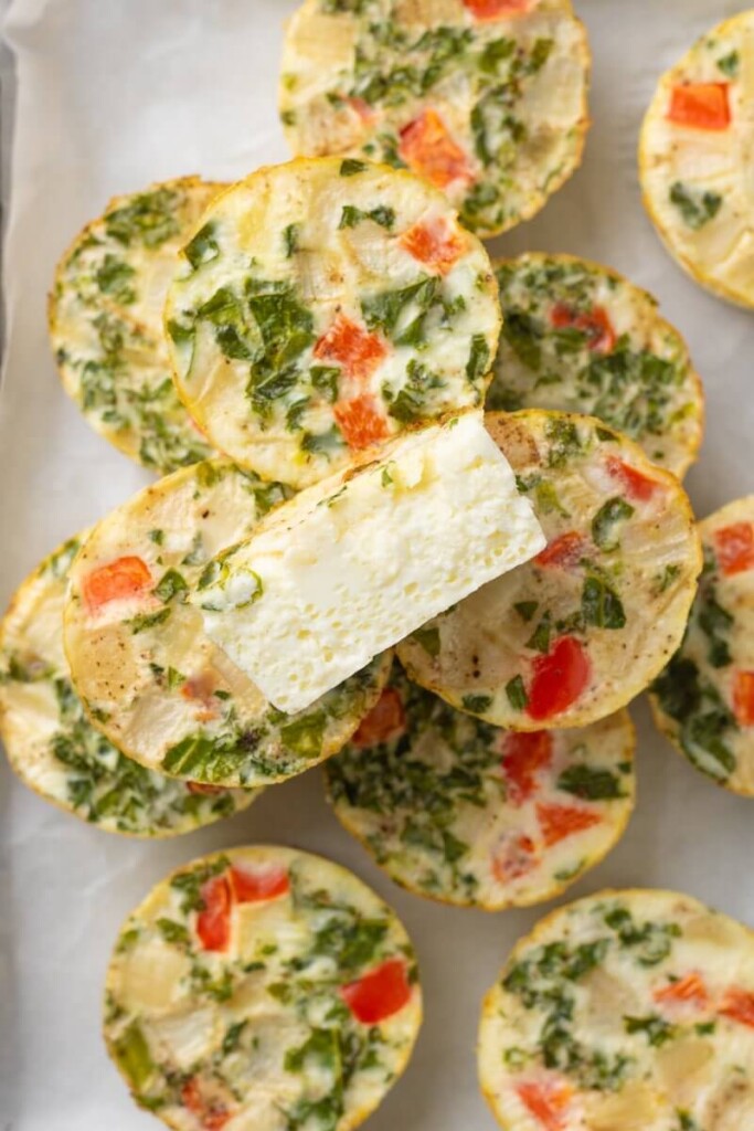 Egg white cups on plate with one egg cup cut in half showing the inside of the egg bite.