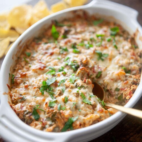 Creamy rotel chicken bake cooked in white baking dish with gold spoon.