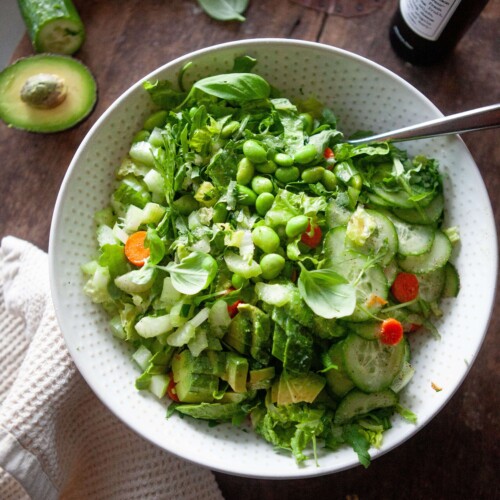 Ingredients for house salad mixed together and served in a bowl with fork on the side.