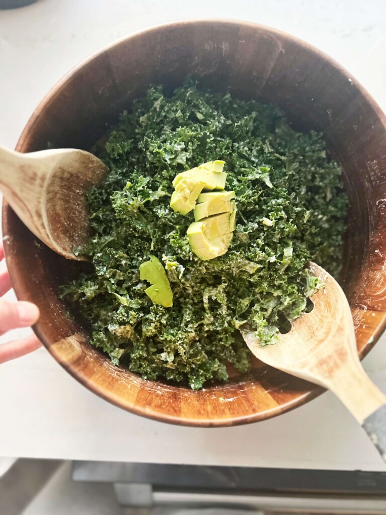 Kale caesar salad prepared and tossed in wooden salad bowl.