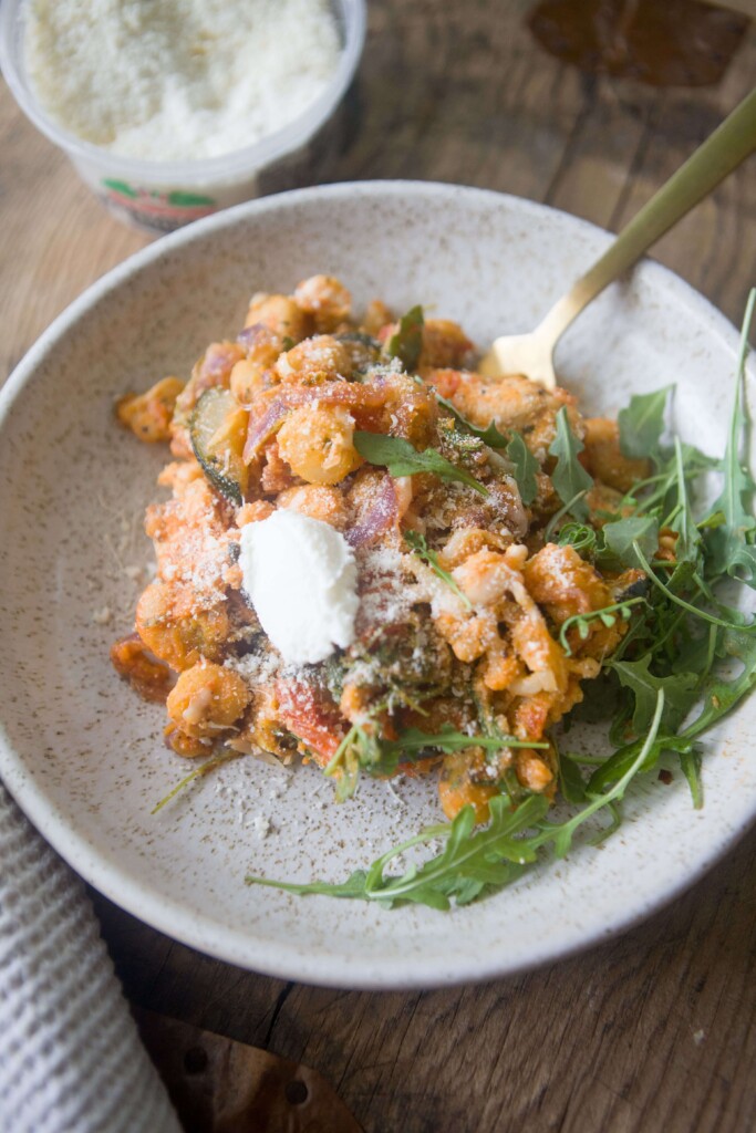 Gnocchi dinner served in a bowl with extra ricotta cheese and arugula.