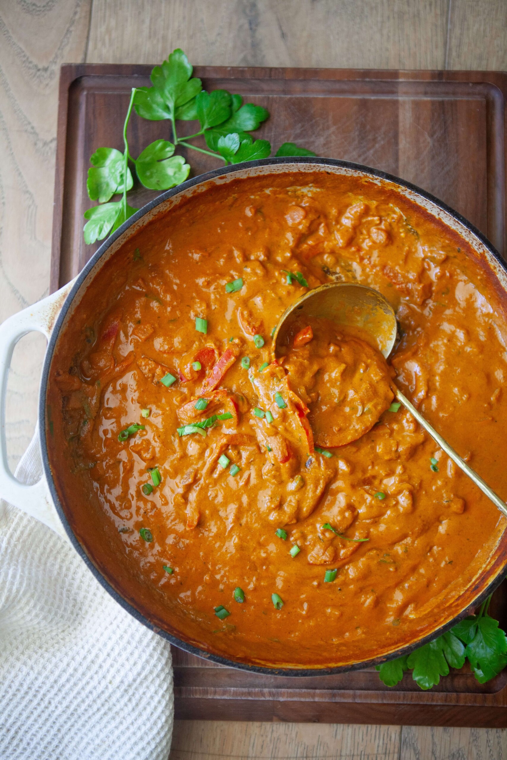 Coconut curry in pan with ladle scooping it up.