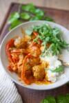 Coconut curry with meatballs rice an arugula in a bowl.