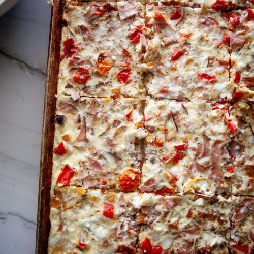 Sheet pan roasted veggie egg bake cooked and sliced on large sheet pan.