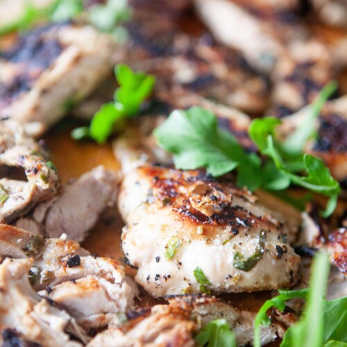 Honey chipotle chicken thighs on cutting board topped with fresh cilantro.