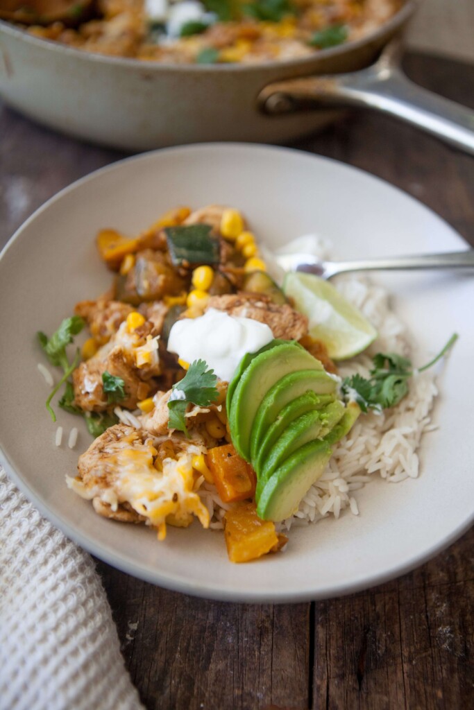Zucchini corn chicken skillet served in a bowl with toppings.