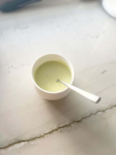 Avocado caesar dressing in small bowl with spoon.