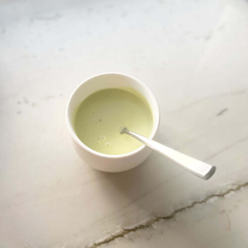 Avocado caesar dressing in small bowl with spoon.