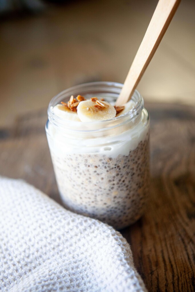 Spoon digging into jar of banana pudding overnight oats.