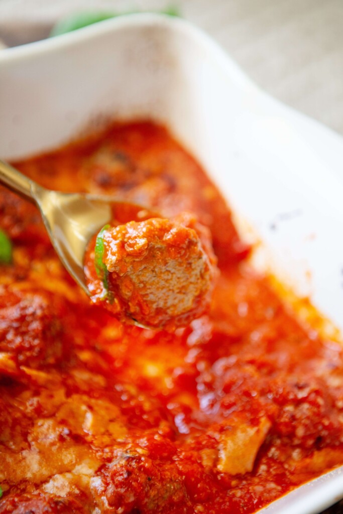Spoon holding cottage cheese meatball out of pan.