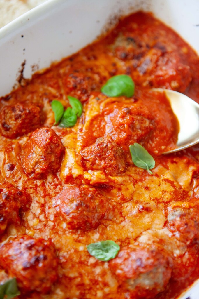 Upclose of spoon scooping cottage cheese meatball out of 9x13 pan.