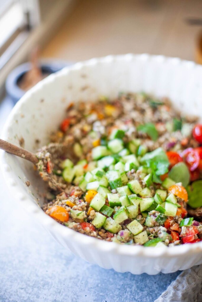 Mixing together ingredients for lentil salmon salad in large bowl.