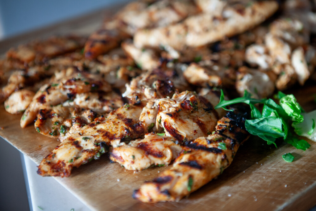 The best marinated grilled chicken on a cutting board with herbs.