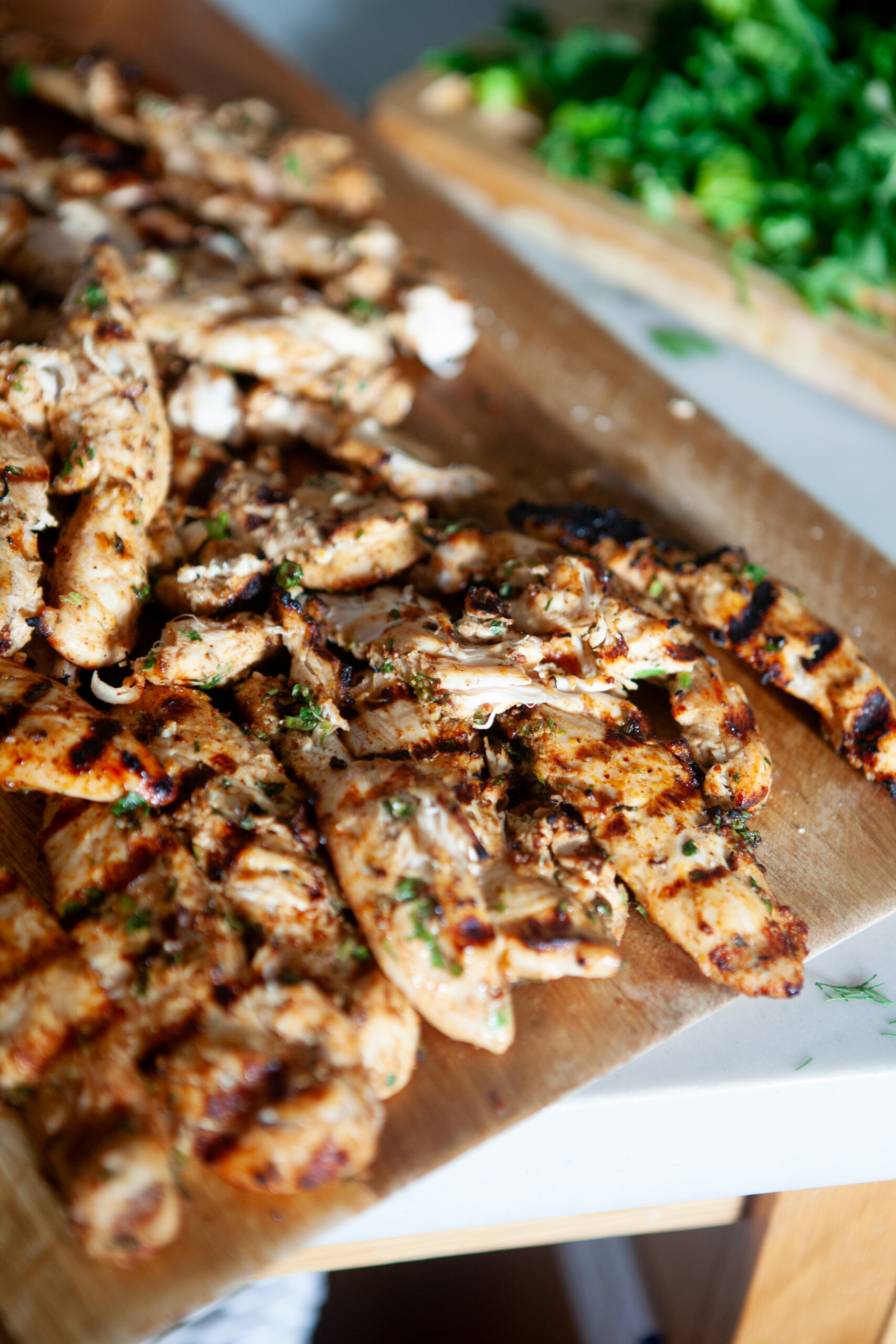 The best marinated grilled chicken on a wooden cutting board with grill marks.