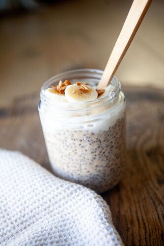 Chia oats in a jar with toppings and a spoon.