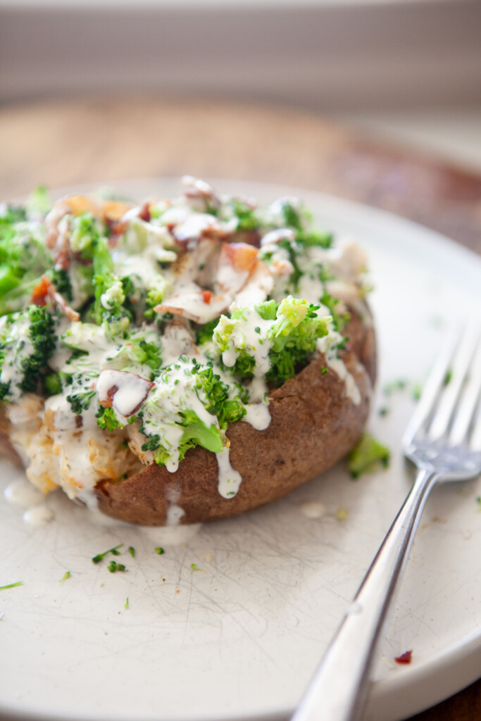 Crispy-skinned broccoli cheese baked potato topped with broccoli, bacon, and creamy herb sauce.