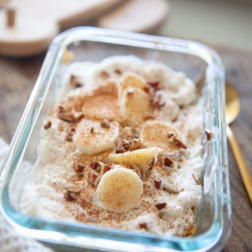 Close-up of a banana butternut baked oat bowl with creamy topping, fresh banana coins, and a sprinkle of cinnamon