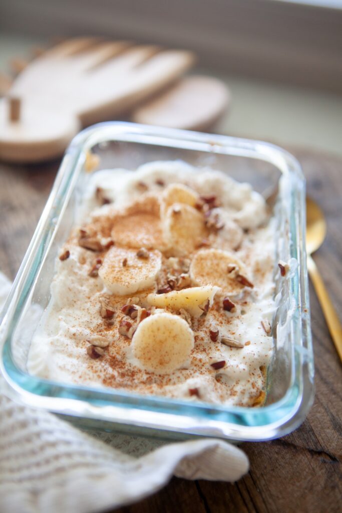 Close-up of a banana butternut baked oat bowl with creamy topping, fresh banana coins, and a sprinkle of cinnamon