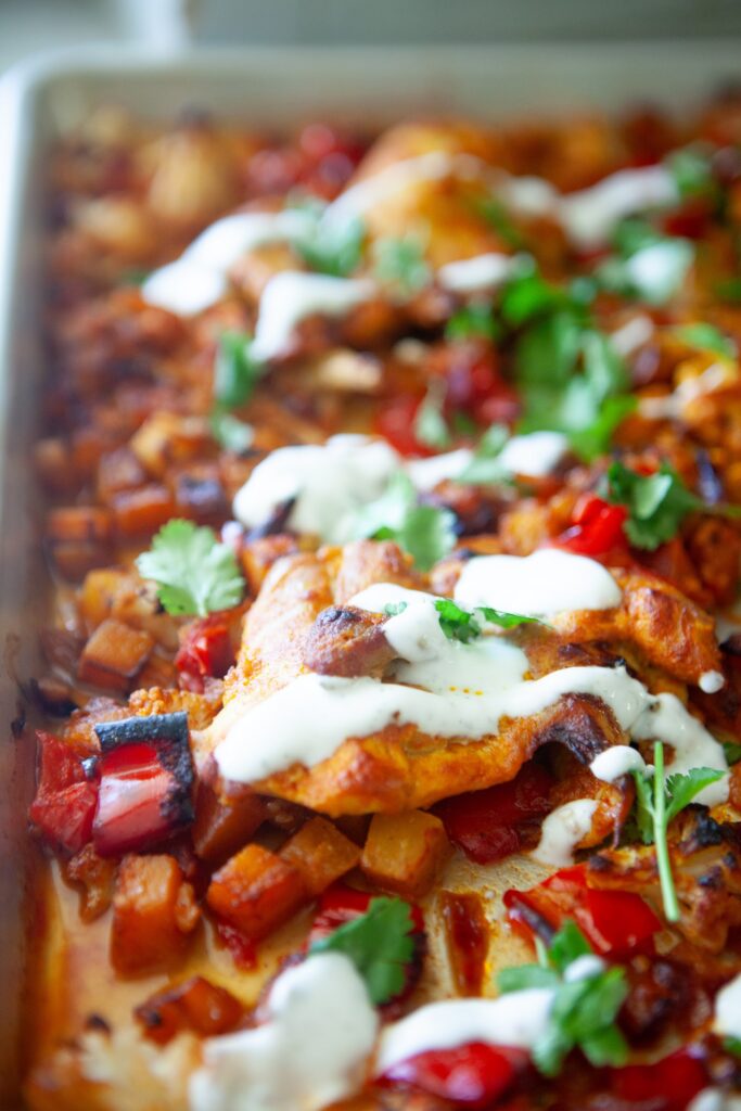 Broiled Moroccan chicken thighs over roasted butternut squash and red bell pepper with yogurt sauce