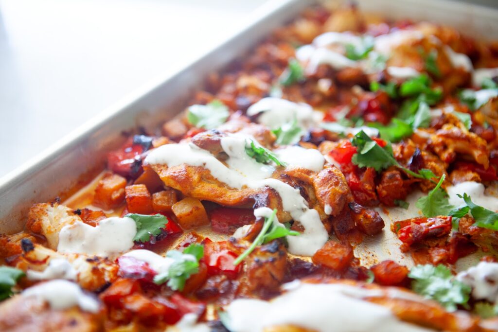 Roasted butternut squash, cauliflower, tomatoes, and red onion with Moroccan chicken on a sheet pan