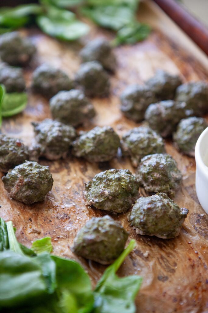 Spinach basil meatballs fresh out of the oven on a baking sheet